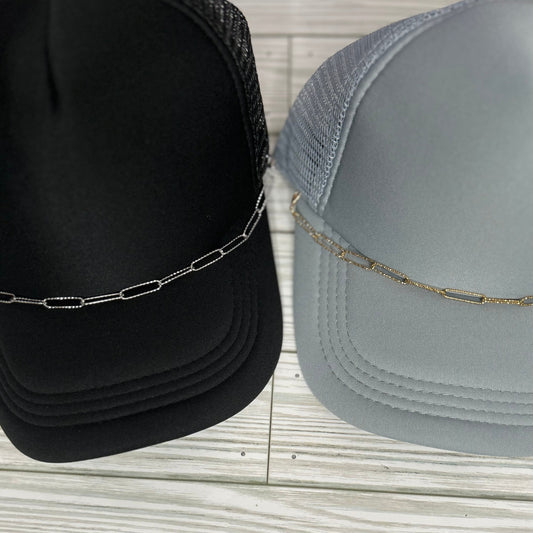 Embossed silver and gold paperclip trucker hat chain on a black and grey hat