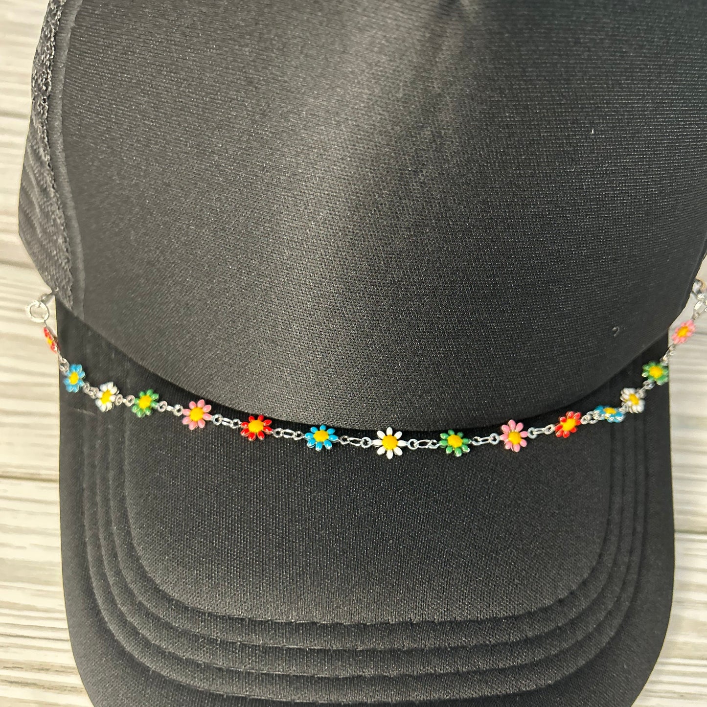 Multi colored daisy trucker hat chain on a black hat