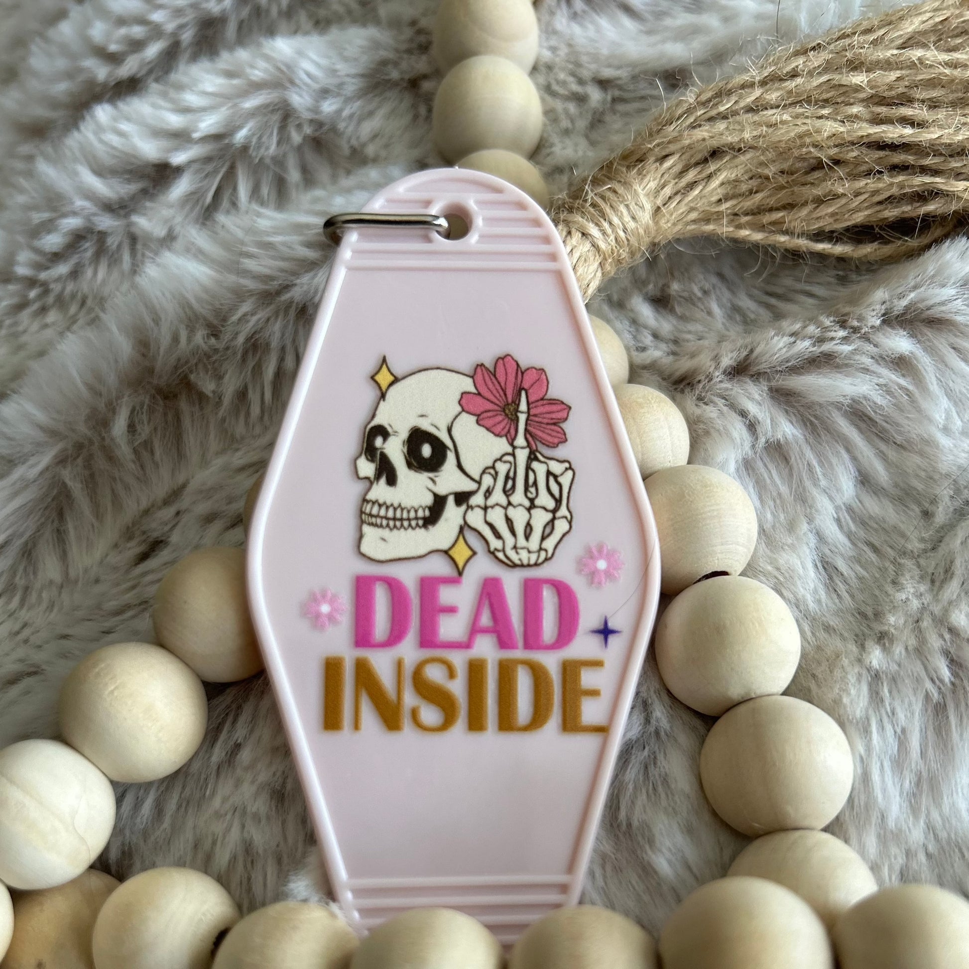 Retro style motel keychain made of plastic with a skeleton design that says dead inside